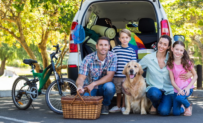 family of four standing behind van with dog